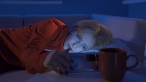 Woman-looking-sad-at-message-on-phone-while-sleeping.